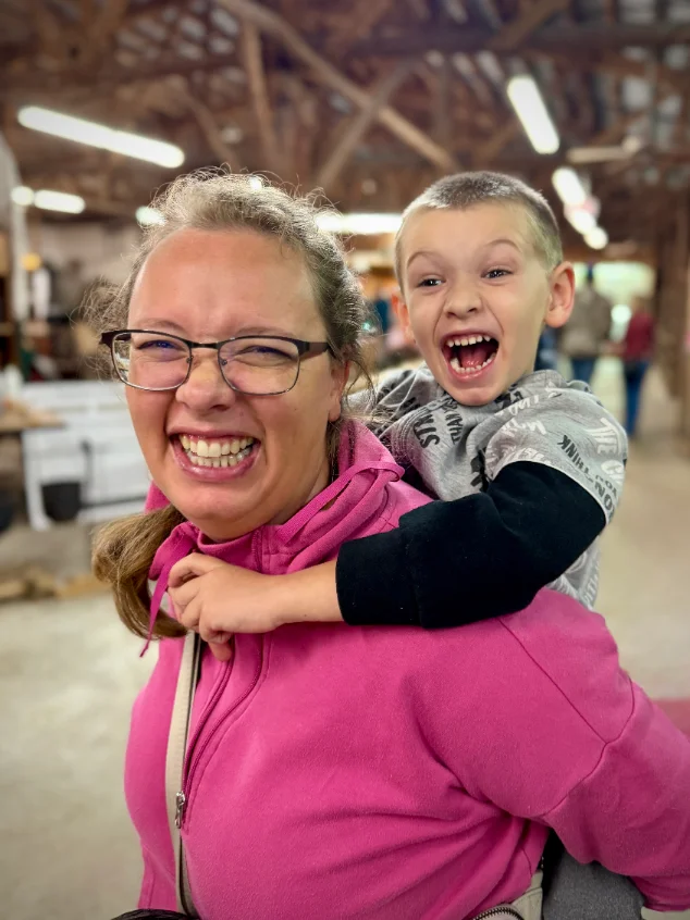 Amber laughing with her son on her back at a local fair.